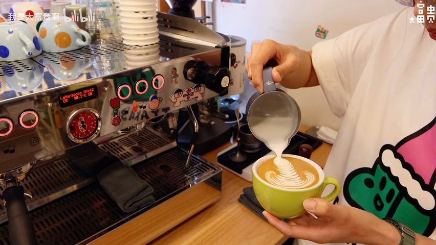 The barista forms latte art in the green cup